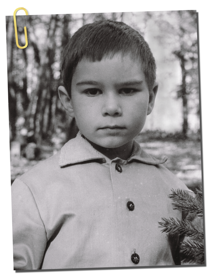 фотография мальчика, стоящего в сосновом лесу и задумчиво и спокойно смотрящего в объектив