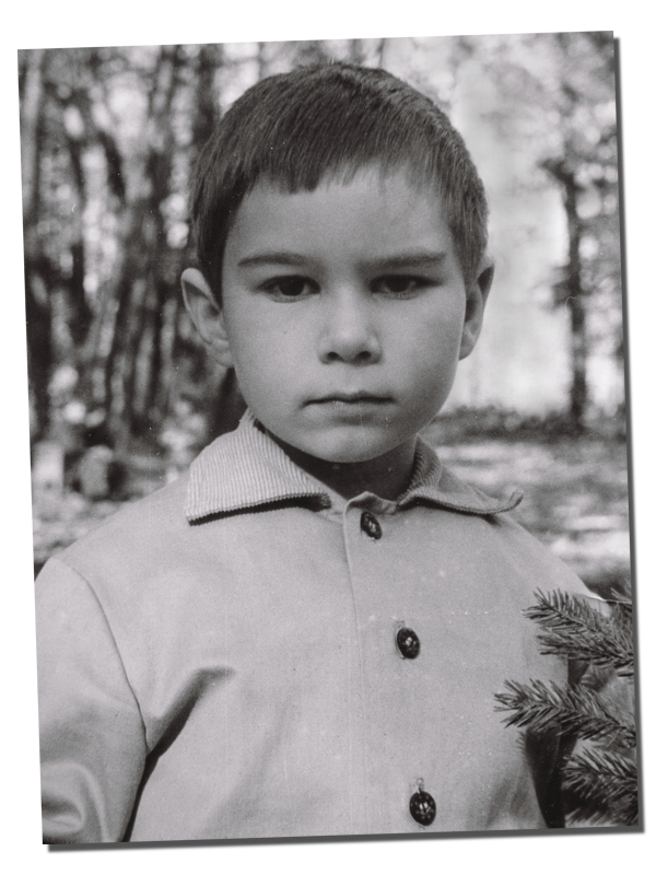 фотография мальчика, стоящего в сосновом лесу и задумчиво и спокойно смотрящего в объектив